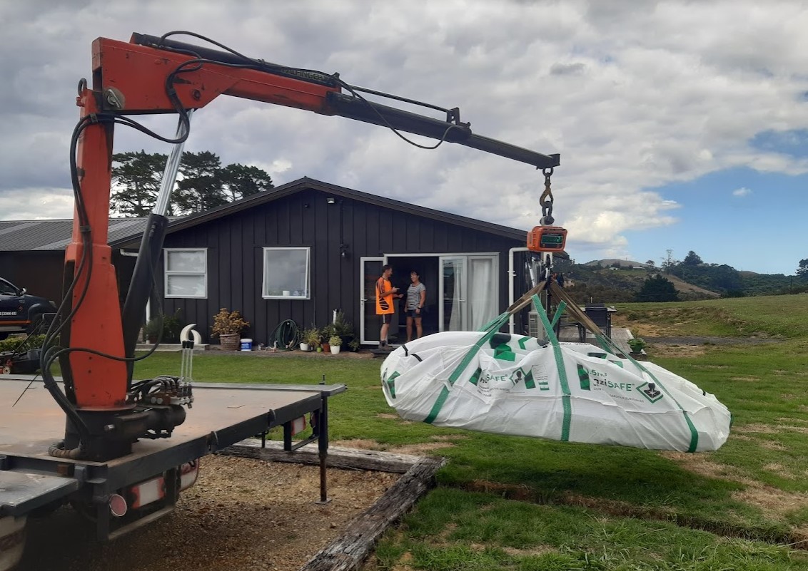 asbestos load lifted with small crane on trailer